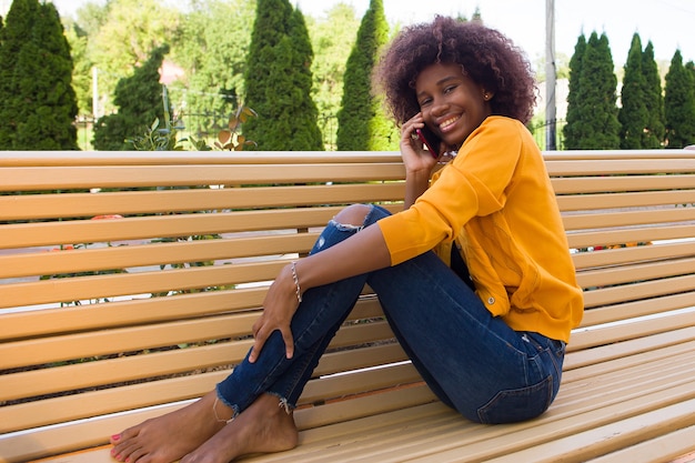 La mujer afroamericana feliz en la calle hablando por teléfono