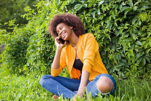 La mujer afroamericana feliz en la calle hablando por teléfono