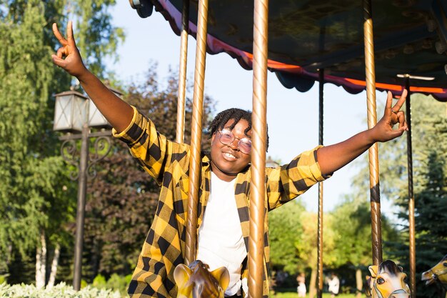 Una mujer afroamericana feliz en el parque en un parque de atracciones en el verano.