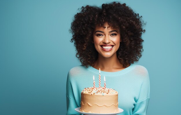 Mujer afroamericana feliz con pastel de cumpleaños y sombrero de fiesta sobre fondo azul