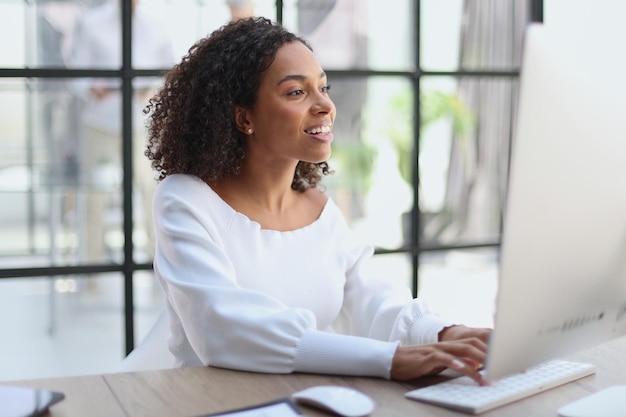 Mujer afroamericana feliz usando estudio de trabajo portátil en la oficina