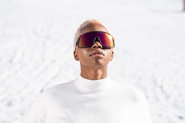 Una mujer afroamericana con gafas de nieve en una montaña nevada durante el invierno