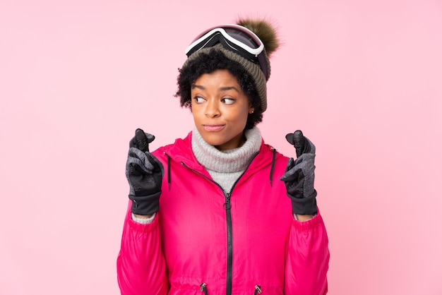Mujer afroamericana con gafas de nieve sobre pared rosa