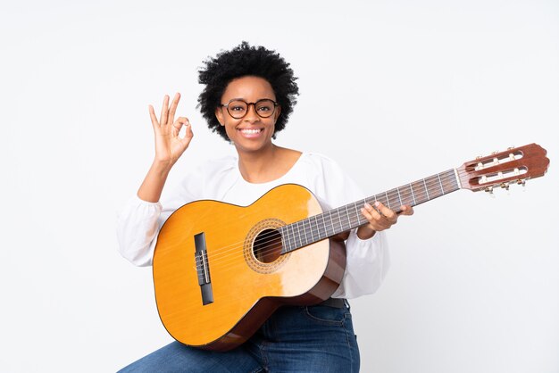 Mujer afroamericana con una guitarra sobre pared blanca aislada