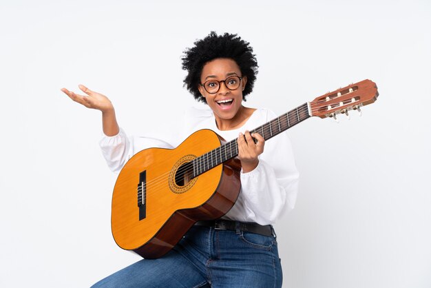 Mujer afroamericana con una guitarra sobre pared blanca