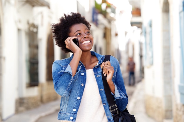 Mujer afroamericana hablando por teléfono móvil y sonriendo al aire libre