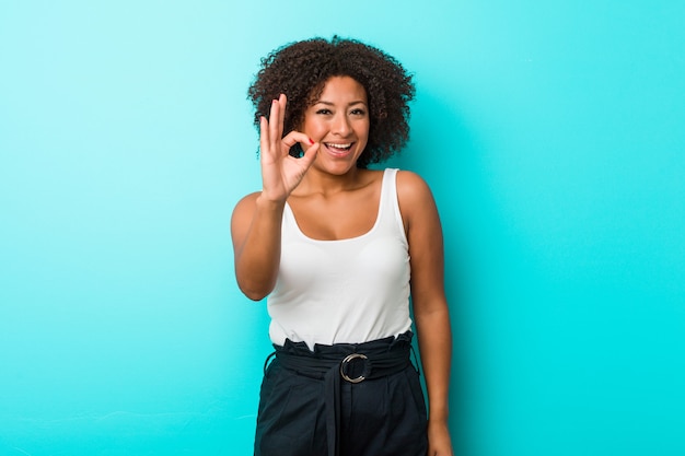 Mujer afroamericana joven alegre y confidente que muestra gesto aceptable.