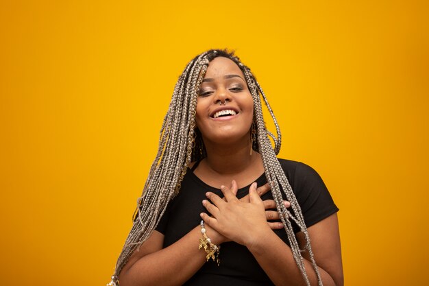 Mujer afroamericana joven hermosa con el pelo del pavor con las manos en su corazón