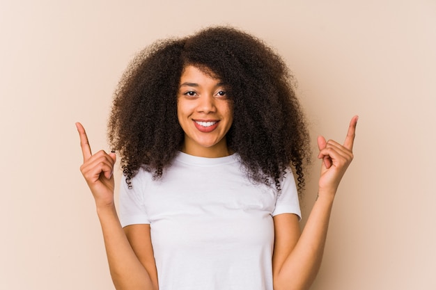 La mujer afroamericana joven indica con ambos dedos delanteros que muestran un espacio en blanco.