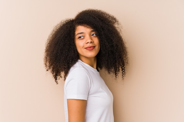 La mujer afroamericana joven mira a un lado sonriente, alegre y agradable.