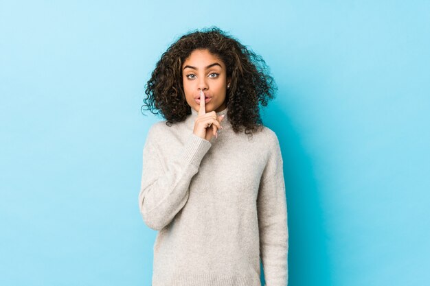 Mujer afroamericana joven del pelo rizado que guarda un secreto