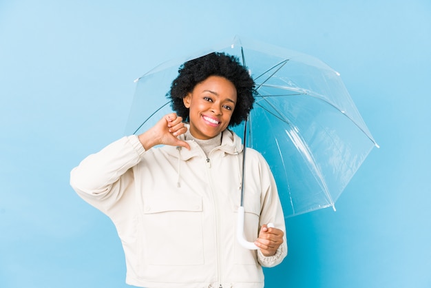 La mujer afroamericana joven que sostiene un paraguas aislado se siente orgulloso y seguro de sí mismo, ejemplo a seguir.