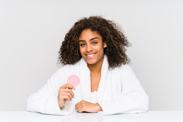 Mujer afroamericana joven que usa un disco facial feliz, sonriente y alegre.