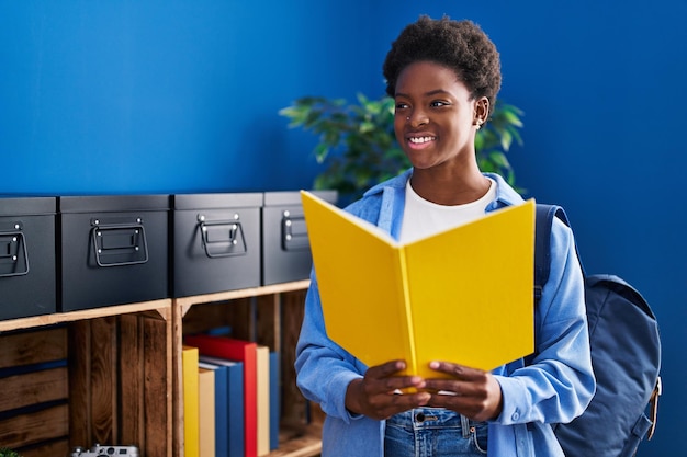 Mujer afroamericana leyendo un libro de pie en casa