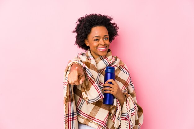 Mujer afroamericana de mediana edad en un camping aislado alegre sonrisas apuntando al frente.