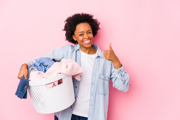 Mujer afroamericana de mediana edad lavando ropa aislado sonriendo y levantando el pulgar hacia arriba