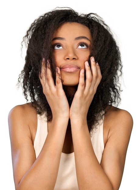 Mujer afroamericana mirando hacia arriba con las manos en la cara, aislado