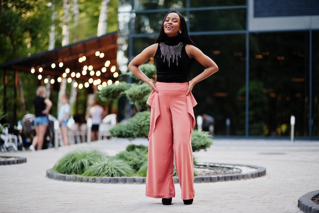 Mujer afroamericana de moda en pantalones de melocotón y blusa negra posan al aire libre