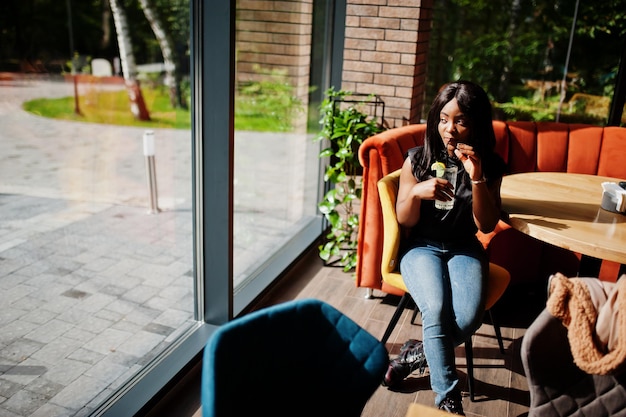 Mujer afroamericana de moda en el restaurante bebe limonada