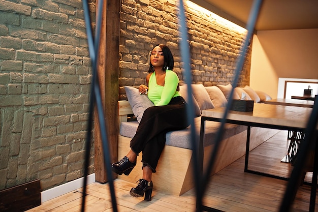 Mujer afroamericana de moda en un top verde claro y pose de pantalón negro