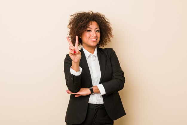 Mujer afroamericana del negocio joven que muestra el número dos con los dedos.
