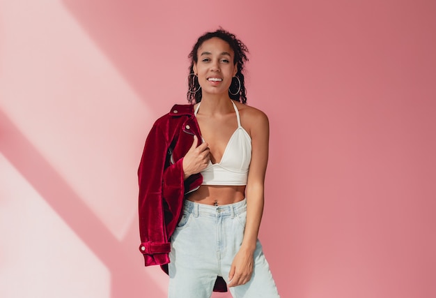 Foto mujer afroamericana negra en jeans con estilo y chaqueta de terciopelo morado, top blanco en rosa