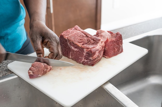 Mujer afroamericana nigeriana cortando carne en tabla de cortar