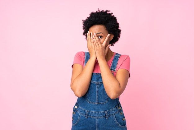 Mujer afroamericana ocultando su rostro con sus manos aisladas sobre fondo rosa