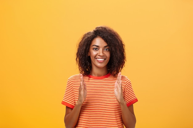 Mujer afroamericana con peinado afro mostrando el tamaño con las manos y sonriendo a la cámara