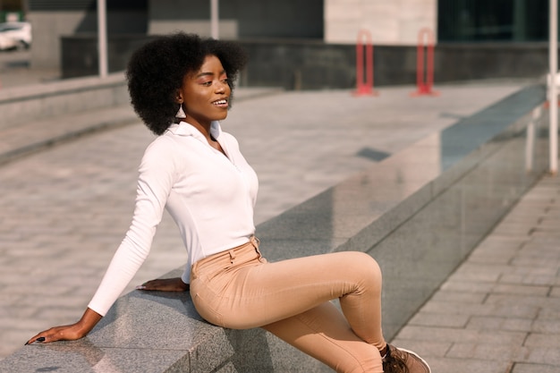 Una mujer afroamericana de piel oscura se sienta en la ciudad