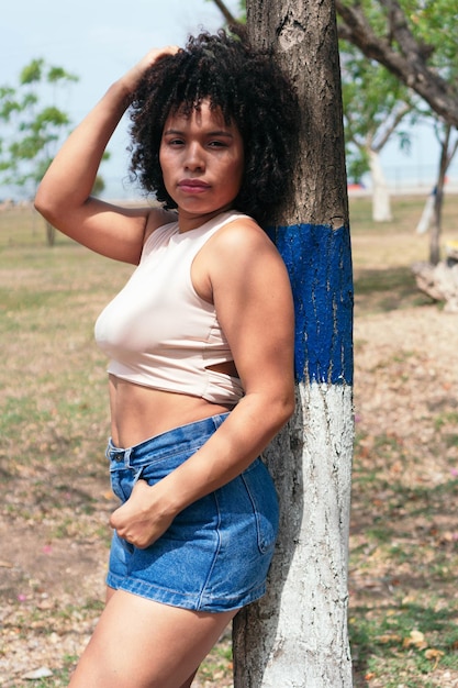 Mujer afroamericana posando en un parque soleado