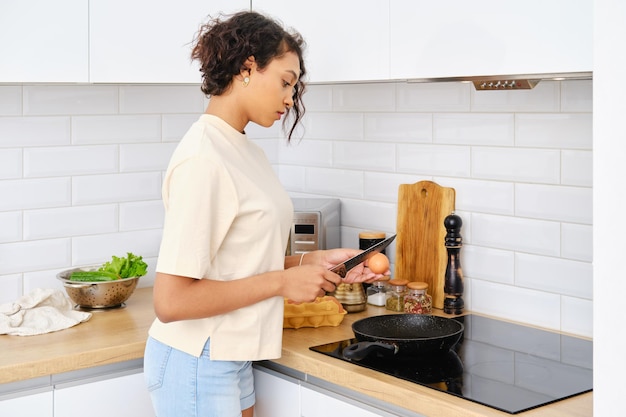 Mujer afroamericana preparando huevos revueltos en casa