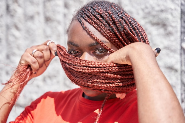 Mujer afroamericana que cubre su rostro con rastas trenzadas rojas