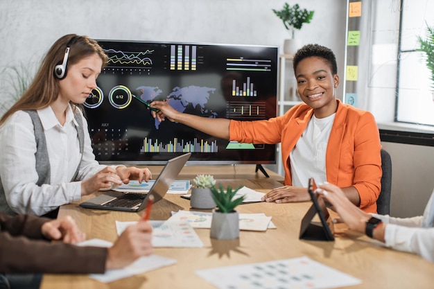 Mujer afroamericana que presenta un informe financiero de la economía mundial en un gran monitor