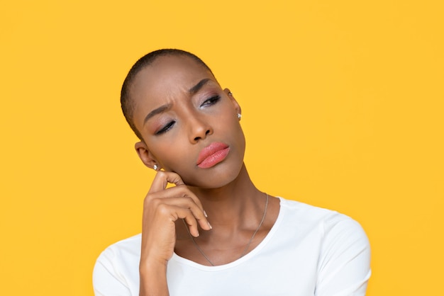 Mujer afroamericana que se siente aburrida en la pared aislada amarilla