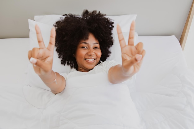 mujer afroamericana sana y alegre en la cama buenos días despierta de buen humor.