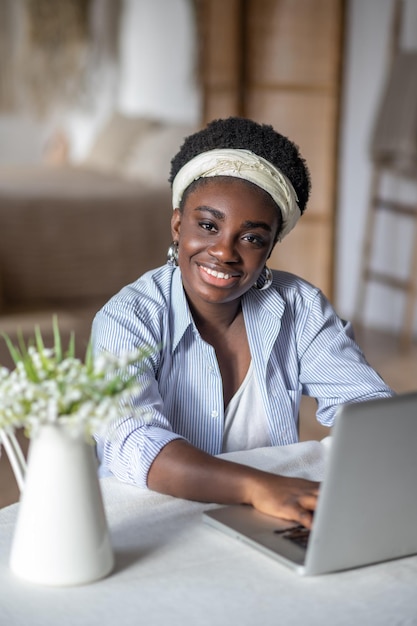 Mujer afroamericana sentada en la mesa y trabajando en una computadora portátil