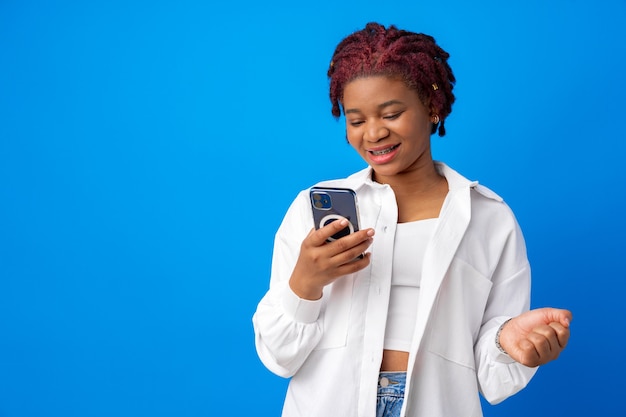 Mujer afroamericana con smartphone contra fondo azul.