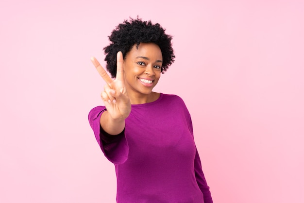 Mujer afroamericana sobre aislados sonriendo y mostrando el signo de la victoria