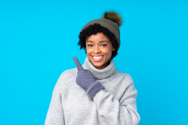 Mujer afroamericana con sombrero de invierno sobre pared azul aislada