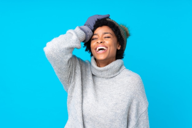 Mujer afroamericana con sombrero de invierno sobre pared azul aislada