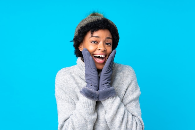 Mujer afroamericana con sombrero de invierno sobre pared azul