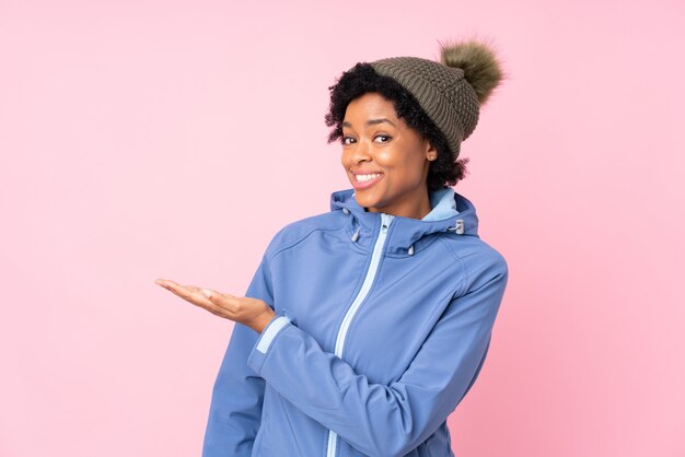 Mujer afroamericana con sombrero de invierno sobre pared rosa aislado