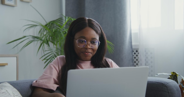 Mujer afroamericana sonriendo comenzando un chat de video en una computadora portátil y saludando