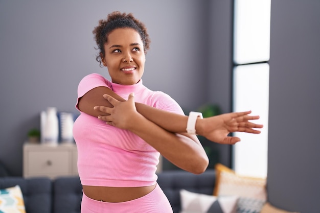 Mujer afroamericana sonriendo confiada estirando el brazo en casa