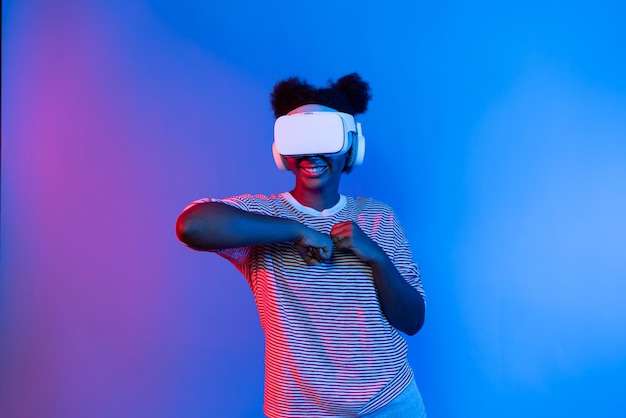 Una mujer afroamericana sonriente con auriculares VR jugando a un juego de boxeo.