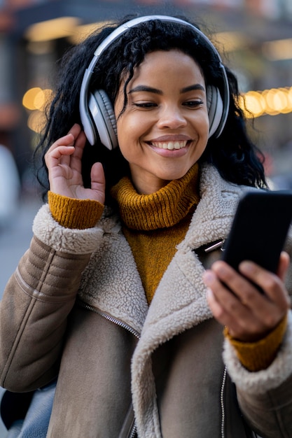 Foto mujer afroamericana sonriente escuchando música fuera