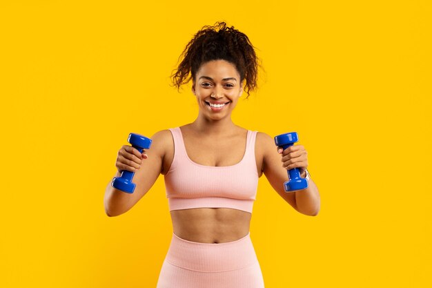 Una mujer afroamericana sonriente haciendo ejercicio con pesas.