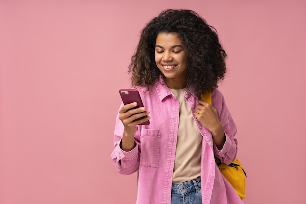 Mujer afroamericana sonriente que usa un teléfono móvil para comprar en línea leyendo un mensaje de texto