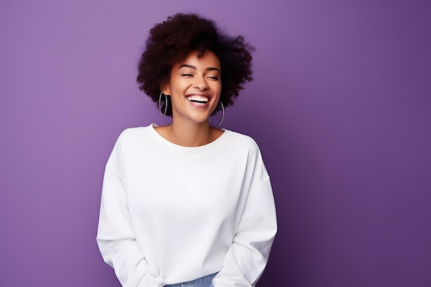 Una mujer afroamericana sonriente con un suéter blanco en la parte delantera en un fondo de estudio púrpura